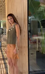 Top color beige de cuero con flecos en los laterales y caracoles buzios en el frente. Espalda tejida.