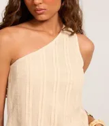 Blusa de algodón color crema con textura de rayas verticales y escote asimétrico de un solo hombro.