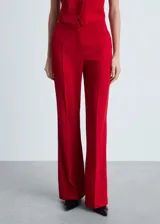 Pantalón de vestir rojo, de corte wide leg y tiro medio. Cuenta con bolsillos laterales y cierre frontal oculto con cremallera, botón y ganchos.
