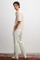 Pantalón color crema en tejido suave de mezcla de algodón, lino y lyocell. Modelo con cierre y botón, elástico revestido en la cintura, pinzas, bolsillos al bies y bolsillos insertados atrás. Corte estándar para una silueta clásica y cómoda.