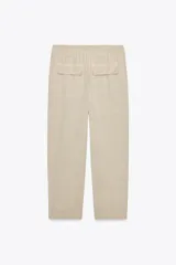 Pantalón gris oscuro de tiro alto con cintura elástica, bolsillos delanteros y falsos bolsillos con solapa en la espalda. Cierre frontal con cremallera y botón.
