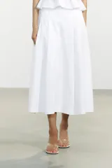 Falda midi blanca de tiro alto con pliegues y bolsillos laterales ocultos. Cierre lateral con cremallera oculta.