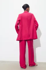 Pantalón de tiro alto color fucsia, con bolsillos delanteros y falsos bolsillos de vivo en la espalda. Tejido con efecto arrugado, pernera recta y cierre frontal con cremallera, botón interior y gancho.