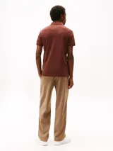 Chomba color ladrillo de Tommy Hilfiger, corte slim, con cuello clásico, tapeta de dos botones y logo bordado en el pecho.