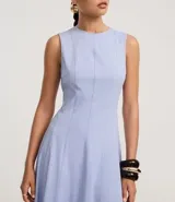 Vestido sin mangas, largo midi, color celeste claro, con escote redondo y corte evasé. Presenta breteles anchos y cierre trasero con cremallera.