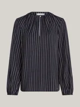 Blusa de viscosa con estampado de rayas verticales blancas sobre fondo azul marino, cuello redondo con abertura en V, cierre de lágrima en la parte delantera y mangas largas con puños fruncidos.