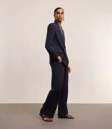 Pantalón de vestir azul marino, de corte wide leg, con cintura alta, bolsillos laterales y traseros. Se ajusta a la cintura con cinturón de cuero marrón.