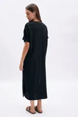 Vestido corto negro de manga corta y cuello redondo, con textura en la tela y corte recto y holgado.