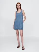 Vestido corto de jean azul, corte recto, sin mangas y con breteles anchos.