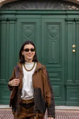 Campera bomber marrón con mangas y parte inferior en denim negro desgastado.