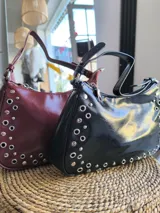 Cartera de cuero color borgoña con tachas plateadas.
