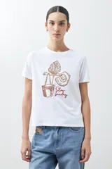 Remera blanca de algodón con estampa de motivos playeros en tonos marrones.