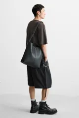 Bolso tipo shopper color negro, con compartimento principal con cierre mediante imán y bolsillo plano interior. Asa de hombro ajustable.