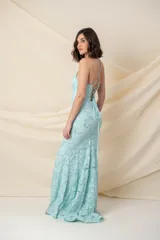 Vestido largo de fiesta color celeste agua marina, con breteles finos, corsé armado y falda con cola de sirena. El vestido está confeccionado en encaje bordado con lentejuelas plateadas.