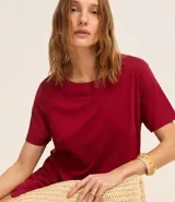 Vestido corto marrón, estilo camiseta, con escote redondo, mangas cortas y bolsillos laterales. El bajo es redondeado.