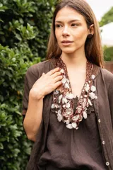 Collar de hilos tejidos color marrón con escamas de pescado y detalles de nácar blanco.