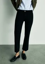 Pantalón de jean negro con tiro medio, corte acampanado y bajo deshilachado. Presenta cuatro bolsillos y cierre de cremallera con botón.