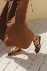 Sandalia de cuero trenzado multicolor, con diseño artesanal y cierre lateral con hebilla.