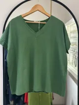 Remera verde oliva de manga corta y cuello en V, con corte holgado y dobladillos en las mangas.