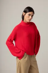 Sweater rojo de punto con cuello alto y mangas largas acampanadas.