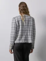 Chaqueta en tejido tweed a cuadrillé blanco y negro, marca Nanette. Cuello a la base y abertura central. Delantera con bolsillos aplicados. Manga larga, puño con botones. Terminación desflecada. Forro interno.