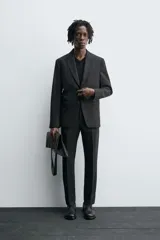 Blazer negro regular fit confeccionado en tejido de lana. Cuello con solapas de muesca y manga larga acabada en puño con botones. Bolsillos de vivo en pecho y de solapa en cadera. Detalle de bolsillo interior. Bajo con aberturas en espalda. Cierre frontal de botonadura.