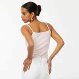 Camiseta sin mangas rosa de canalé con tirantes finos y detalle de encaje con moño en el escote.