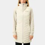 Chaleco largo acolchado Columbia Joy Peak II Long para mujer, color crema. Cuenta con cuello alto forrado en polar, cierre frontal bidireccional, bolsillos laterales con cierre y tecnología Omni-Heat Infinity en el forro interior. El aislamiento Thermator de poliéster reciclado brinda calidez ligera.