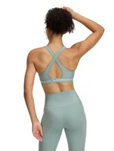 Top deportivo Under Armour color verde agua, con espalda cruzada y logo de la marca en la banda inferior.