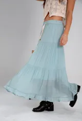 Falda larga celeste de algodón y viscosa, con cintura elástica y cordón ajustable. Diseño escalonado con tres volados.