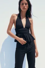 Top negro de cuello halter y escote pico con volantes en el bajo.