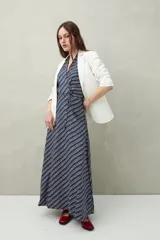 Vestido largo azul con rayas blancas diagonales y estampado de lunares. Diseño cruzado con escote halter y lazo al cuello.