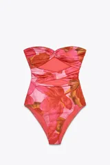 Traje de baño enterizo strapless con estampado floral en tonos rosados y rojizos. Presenta escote corazón con nudo central, detalle cut out en el abdomen y copas extraíbles.