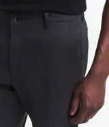 Pantalón de vestir color beige, de corte slim, con bolsillos laterales y traseros. Se ajusta a la cintura con cinturón de cuero negro.