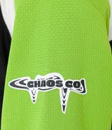 Remera de poliéster negra con mangas raglán verde lima y detalles blancos en los hombros. Presenta estampados con tipografías y gráficos en blanco en el frente.