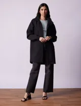 Gabardina negra impermeable con capucha desmontable, cierre central con cremallera y botones a presión, bolsillos delanteros y forro interno.