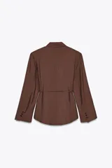 Blazer marrón con cuello solapa, manga larga con hombreras y cierre frontal con botones. Incluye cinturón fino del mismo tejido para ajustar a la cintura.