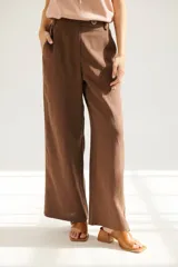 Pantalón de lino azul de corte palazzo con botón decorativo en la cintura.