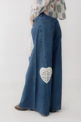 Pantalón de jean azul de corte wide leg con aplicaciones de crochet en forma de corazón, trébol, diamante y pica.