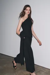 Pantalón de tiro medio confeccionado en hilatura con mezcla de viscosa, color negro. Presenta bolsillos laterales ocultos en costura, bajo acabado en puño con botones y cierre frontal con cremallera, botón y ganchos metálicos.