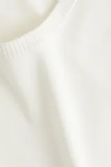 Remera de punto fino color blanco, de manga corta y cuello redondo, con terminaciones acanaladas en puños y bajo.