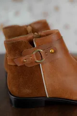 Bota corta negra de cuero con detalle de hebilla metálica y elástico en el tobillo.