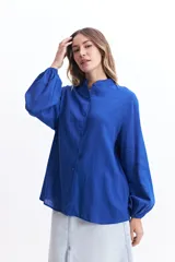 Camisa azul de manga larga con cuello mao, corte holgado y cierre frontal con botones.