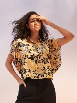 Camisa de manga corta con estampado de flores en tonos amarillo, negro y beige.