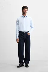 Camisa celeste de corte regular, con cuello italiano, mangas largas con puños abotonados y cierre frontal con botones.