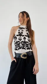 Top de seda estampado en blanco y rojo, con cuello halter y lazo en la espalda.