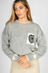 Sweater gris de lana con cuello redondo y manga larga. Tiene un bolsillo en el pecho con un diseño de corazón a rayas en blanco y negro.