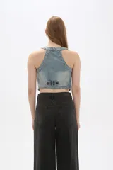 Chaleco de jean celeste sin mangas, con cuello en V, cierre frontal con botones y dos bolsillos con solapa en el pecho.