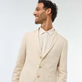 Blazer color beige de lino, corte slim, con solapa de muesca, cierre de dos botones, bolsillo en el pecho y bolsillos delanteros con solapa.