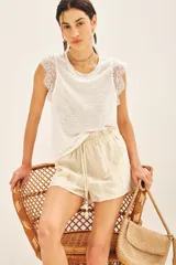 Musculosa blanca de lino con detalle de encaje en mangas y cuello. Tiene bordado de alas en el bajo.